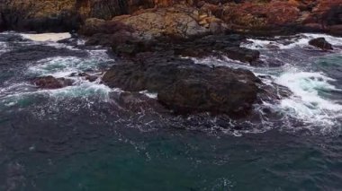 Güneş ufukta batarken, güçlü dalgalar acımasız bir şekilde dalgalanır. Sıcak renkler süzülür ve güzelliklerle dolu sakin bir sahil sahnesi yaratır..