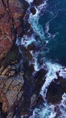 Güneş batmaya başladığında dalgalar engebeli kayaların üzerinde dalgalar dalgalanır, gökyüzünü sıcak renklerle boyarlar. Bu nefes kesici sahil sahnesi, sahil boyunca doğanın güzelliğini yansıtıyor..