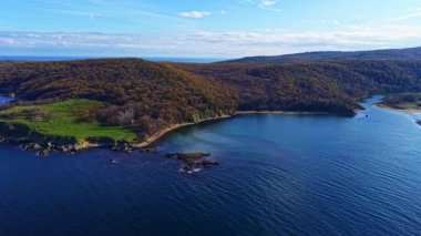 Nefes kesen bir manzara, yemyeşil yemyeşil ile ışıl ışıl mavi suyun buluştuğu sakin bir kıyı şeridini gözler önüne serer. Dalgalar sahili öperken uzak tepeler parlak bir gökyüzünün altında yükseliyor..