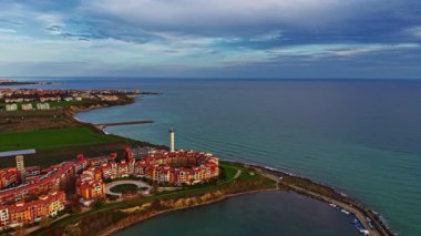 Deniz kenarındaki canlı bir tatil köyü alacakaranlıktaki büyüleyici renkleri yakalar. Dalgalar yavaşça kıyıya vururken bulutlar gökyüzünde dans ederken doğanın güzelliğini gösteriyor..