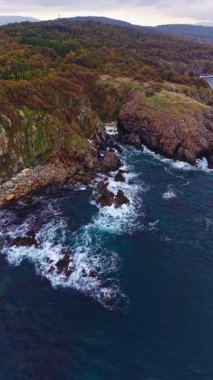 Dalgaların kayalara çarptığı derin mavi denizden engebeli uçurumlar yükseliyor. Sonbahar renkleri manzarayı güzelleştirir, doğanın güzelliğini huzurlu ve güçlü bir şekilde gösterir..