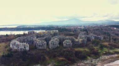 Terk edilmiş bir oluşumun çökmekte olan yapıları, sakin bir su kütlesine göz yumar. Doğanın yavaş yavaş yeniden ele geçirildiği bir ortamda hayat durur..
