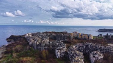 Çökmüş yapılar kıyı boyunca sessizce durur. Dalgalar unutulmuş alanın kenarlarına hafifçe vurur..