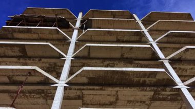 İşçiler, güneş ışığı ham beton formunu aydınlatırken, mimari tasarım ve kentsel gelişimin güzelliğini gözler önüne seren modern bir bina inşa ediyorlar..