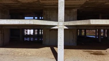 Beton bir iskelet, yerde benzersiz gölgeler yaratan kesişen kirişler şeklinde dimdik ayakta duruyor. Kentsel gelişim mesafeyi açtıkça güneş ışığı açıklıklardan süzülür.