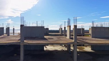 Bitmemiş beton yapılar uçsuz bucaksız bir alana yayılmış durumda. Gün ortası güneşinin tadını çıkarıyor. Yukarıda mavi gökyüzü ve uzakta doğanın işaretleri var..