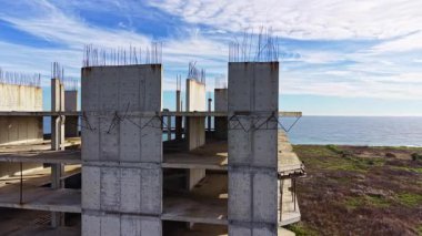 Güzel kıyı şeridine bakan çağdaş bir binanın inşaatı devam ediyor. Beton yapılar bulutların ve okyanus dalgalarının dingin zeminine doğru gökyüzüne uzanıyor..
