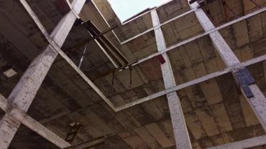 Açık gökyüzüne doğru yükselen eski beton sütunlar uzun zaman önce terk edilmiş karmaşık bir yapıyı ortaya çıkarıyor. Gölgeler yıpranmış yüzeylerde oynarlar. Hem tarihi hem de kaybı ima ederler..