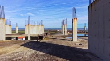 Bitmemiş inşaatın ortasında beton sütunlar gökyüzüne doğru yükseliyor. Açık bir günde, gölgeler çorak topraklar boyunca uzanırken doğa kendi alanını geri alır..