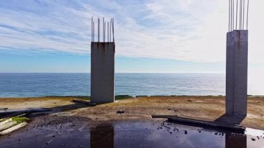 Beton sütunlar gururla yükselir dingin okyanusun kenarında, yumuşak dalgalar yavaşça kıyıya vurur.