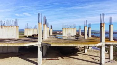 Beton iskeletler mavi gökyüzüne karşı yükselirken paslı demirler yukarı doğru uzanıyor. Bu şantiye potansiyeli ve gelecekteki yapıların vaatleriyle dolup taşıyor..