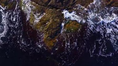 Alacakaranlıkta engebeli kayalara çarpan dalgalar karanın ve denizin büyüleyici çarpışmasını gözler önüne seriyor. Sahne, suyun hareketi ve ışık oyunuyla canlıdır..