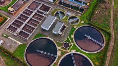 Kuş bakışı görüntülerde, büyük dairesel tankların öğleden sonra aydınlığında suyu verimli bir şekilde işlediği açık bir gökyüzünün altında yeşil bir çevreye yerleştirilmiş bir atık su arıtma tesisi görülüyor..