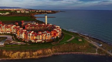 Güzel bir sahil beldesi, berrak güneşli bir gökyüzünün altında canlı yeşil tarlalar ve mavi okyanus sularıyla çevrili, zarif bir şekilde kıyıda bulunur. Sakin atmosfer rahatlamayı davet eder..