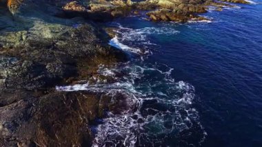 Alacakaranlık, dalgaların engebeli kayalara hafifçe çarptığı kıyı şeridinde altın bir parıltı saçar. Uçsuz bucaksız okyanus ufuk ile kusursuz bir şekilde harmanlanarak sükuneti ve yansımayı davet eder..