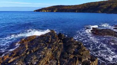Dalgalar engebeli kayalara çarparken sabah ışığı suda dans eder. Kıyı şeridi, şafak vakti barışı ve yansımayı davet eden çarpıcı bir doğal güzelliği gözler önüne seriyor..