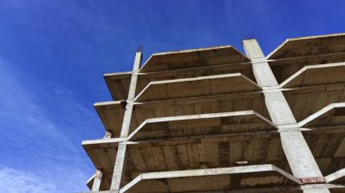 Büyük beton bir yapı, canlı mavi bir gökyüzüne karşı yarım yamalak duruyor. Katı çizgileri ve boş alanları, gelecekteki gelişim ve kentsel dönüşüm vaadini anımsatıyor..