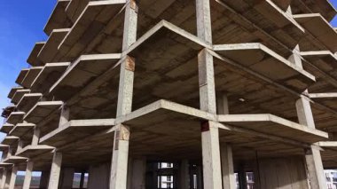 Benzersiz bir manzara, sakin bir ortamda ayakta duran tamamlanmamış beton bir binayı gözler önüne seriyor. Güçlü geometrik çizgiler ve açık alanlar ilginç bir potansiyel atmosfer yaratıyor..