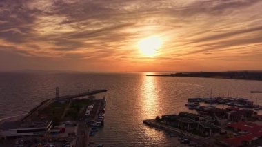 Güneş ufkun altına batarken, gökyüzü sıcak renklerden oluşan bir tuvale dönüşür. Tekneler dalgaların üzerinde usulca dans eder, ve alacakaranlıkta limanı sükunet doldurur.