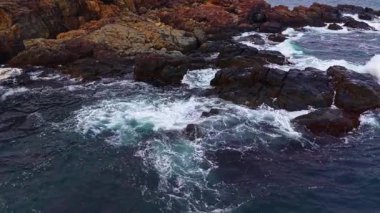 Dalgalar doğanın ham gücünü gösteren köpük ve köpük gibi görkemli kayalar okyanusun derinliklerinden fışkırıyor. Arka planda güneş batar, sahnede sıcak bir parıltı bırakır..