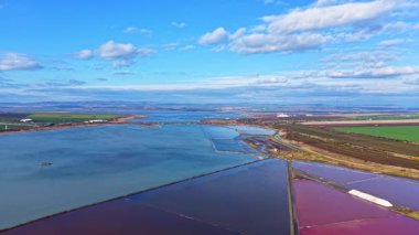 Sahil boyunca parlak renkli tuz düzlükleri uzanıyor, berrak bir gökyüzünün altında parlıyor. Bereketli tarım arazileri ve dingin sular doğal güzelliklerle dolu pitoresk bir manzara yaratır..