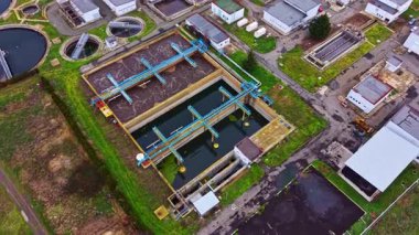 Birden fazla tank ve yapıya sahip büyük bir su arıtma tesisi. Ekipman suyu farklı aşamalardan geçirir. Bölgeyi çevreleyen yeşil alanlar. İşçiler burada olabilir.