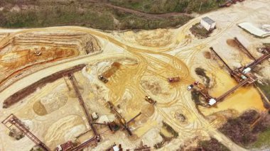 Ağır makineler ve ekipmanlar bir inşaat alanında çalışıyor. Toprak ve çakıl gelişim için arazide taşınır. Gün ışığında kırsal bir alanda ekipmanlar yerleştirildi..