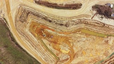 Çamur ve çamurlu suyla dolu bir inşaat alanında ağır makineler çalışıyor. İşçiler kırsal alanda yeni bir proje için zemin hazırlıyorlar.