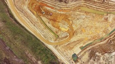 Ağır makineler toprağı hareket ettiriyor ve inşaat alanında kanallar oluşturuyor. Zemin son çalışmalardan izler gösteriyor. Yakında su birikintileri var..