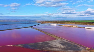 Tuz düzlüklerinin canlı genişliği, alacakaranlıkta gökyüzünün parlaklığını yansıtırken parıldıyor, doğanın sanatsal çalışmalarını, yumuşak tepelerin ve yumuşak bulutların ardında sersemletiyor..
