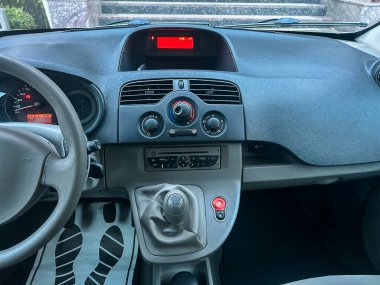 Arabanın içi gösterilir ve gösterge paneli görünür olur. Kontroller, düğmeler ve ses sistemi sürücü koltuğuna erişilebilir durumda. Araç park halinde..