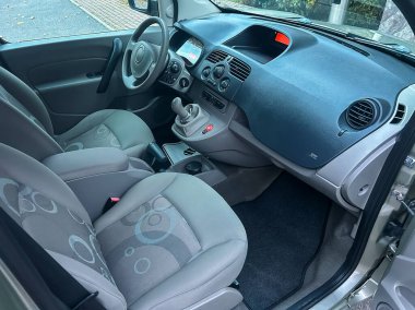 Küçük bir arabanın ön tarafında basit bir gösterge paneli olan iki koltuğu vardır. Açık hava olan bir şehir bölgesinde park halinde. Güneş ışığı pencereden girer..