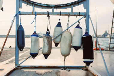 Şamandıralar suya yakın bir rafa konur. Arka planda, tekneler hareket ederken görülebilir. Sahne öğleden sonra, yoğun bir kıyı bölgesini gösteriyor..