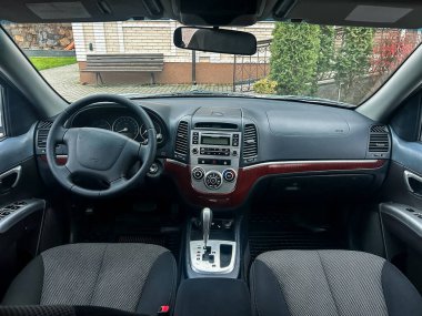 Arabanın içindeki görüntü gösterge paneli, direksiyon simidi ve vites kolunu gösteriyor. Güneş ışığı pencereden içeri giriyor ve ortam özel bir alan..