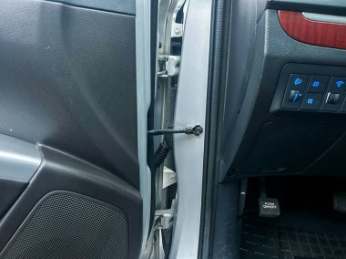 Yakından bakınca, siyah cıvatalı bir araba kapısı menteşesi görünüyor. Aracın içi görünürde, kapıdaki ve kattaki kontroller de dahil..