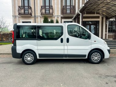 Minibüs, girişi kapalı büyük bir tuğla binanın yanında duruyor. Gökyüzü bulutlu ve bölgede hareket ya da insan belirtisi yok..