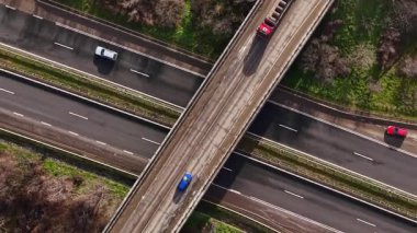 Kuşbakışı bakış açısı birkaç yolun kesiştiğini gösteriyor. Araçlar açık bir gökyüzünün altında otobanlarda hareket ediyor. Yeşil ağaçlar yolları sınırlıyor.
