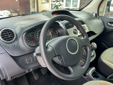 Park halindeki bir arabanın direksiyonu ve gösterge paneli görülebilir. Olay yeri kontrolleri, tuşları ve oturma alanını gösteriyor. Dışarıda kar zemini kaplıyor..