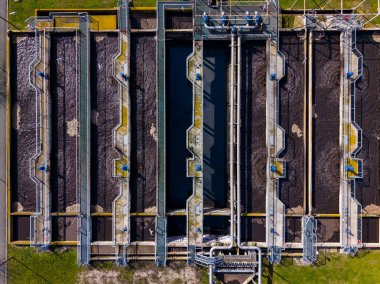 Olay yeri birkaç tankı ve yolu olan bir su arıtma tesisini gösteriyor. Boru sistemleri tüm bölgeye yayılmış durumda. Manzara gündüz vakti yukarıdan çekiliyor..