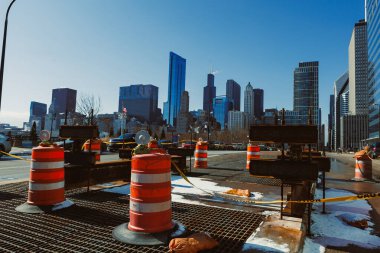 İnşaat işçileri Chicago şehir merkezinde bir site hazırlıyorlar. Trafik konileri ve bariyerler açık bir günde işlek şehir siluetinin yakınındaki bölgeyi işaret ediyor.