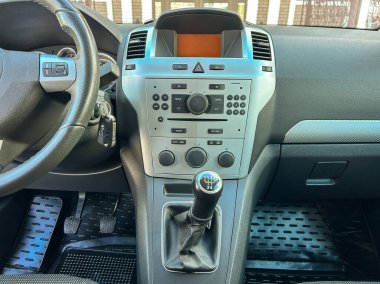 Park halindeki bir arabanın gösterge paneli kontrollü ve vites koluyla görülebilir. Güneş ışığı kabini etkiler. Anahtarlar kontaktan sarkıyor.