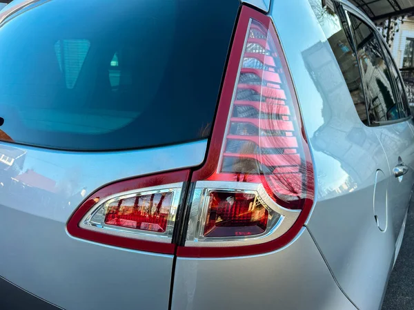 Arabanın arka lambası tasarım ve yapı detaylarını gösteriyor. Bu çekim yüzeyi yakalar ve gündüz vakti bir otoparktan şekillenir..