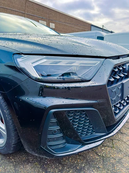 Siyah bir araba bir binanın yanında park edilmiş. Yağmur damlaları, ıslak bir bakış göstererek arabanın yüzeyini kaplıyor. Sahne öğleden sonra gökyüzünde bulutlarla başlar..