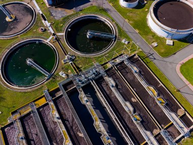 İşçiler atık suyu temizlemek için tasarlanmış bir tesiste su arıtma süreçlerini birkaç tankla yönetiyorlar. Sistemin düzgün işlemesini ve bakımını sağlıyorlar..