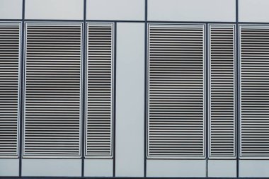 Louvered menfezleri binanın ön cephesinde sıra halinde dizilmiştir. Tasarım düz çizgiler ve paralel çıtçıtlara sahiptir. Güneş ışığı yüzeye gölge düşürür..