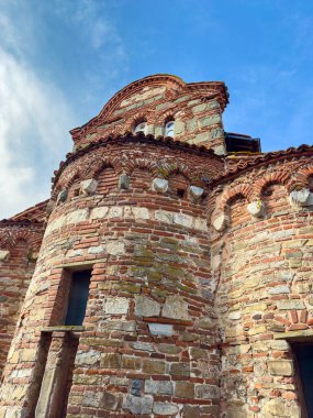 Tuğla ve taştan yapılmış tarihi bir yapı mavi gökyüzüne karşı görülebilir. Bina eşsiz desenlere ve pencerelere sahip, daha önceki zamanlardan kalma bir zanaatkarlık sergiliyor..
