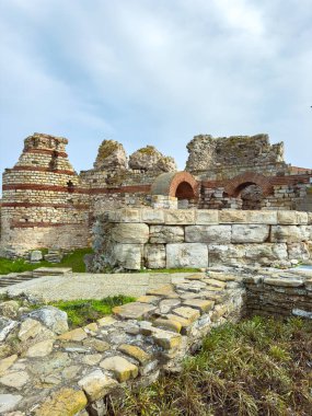 Ziyaretçiler, çimenler ve temiz bir gökyüzüyle çevrili taş ve tuğladan yapılmış eski bir binanın kalıntılarını keşfediyorlar. Mimaride tarih ve zaman belirtileri var..