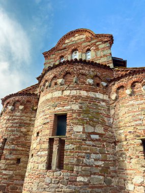 İnsanlar tuğladan yapılmış tarihi bir kiliseyi görebilir. Bina yuvarlak şekilli ve küçük pencereli eşsiz bir mimari gösteriyor. Bir köyde açık mavi bir gökyüzünün altında duruyor..
