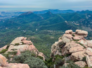Kayalar yüksek tepelerde oturur ve yeşil tepeleri ve uzak okyanusu görürler. Manzara gün ortasında açık bir gökyüzünün altında birçok ağaç ve dağ içerir..