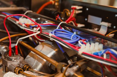 Bir atölyede mekanik cihazın parçalarını farklı renklerde birbirine bağlayan kablolar. Cihaz ve teçhizat, cihazın onarımında kullanılıyor..